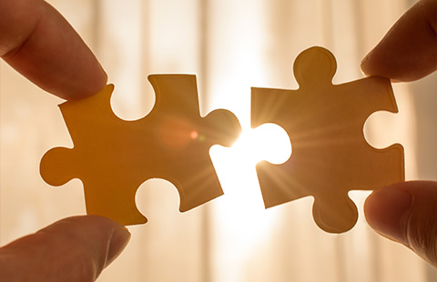 two yellow puzzle pieces being connected with sunlight in the background symbolizing eight connections and unity