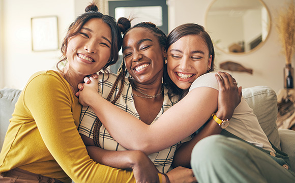 three happy friends hugging on a couch warm smiles joyful atmosphere friendship 4 ways to connect